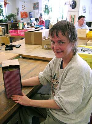 Eine Mitarbeitering entfernt Aufkleber von alten Cds