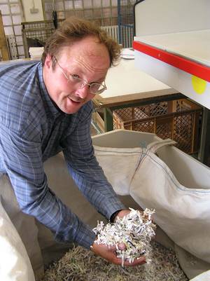 Ein Mann zeigt die zerkleinerten Streifen der vernichteteten Dokumente.